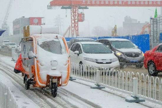  2020年2月14日，北京迎來降雪天氣，快遞小哥忙著送貨。圖 | 視覺中國